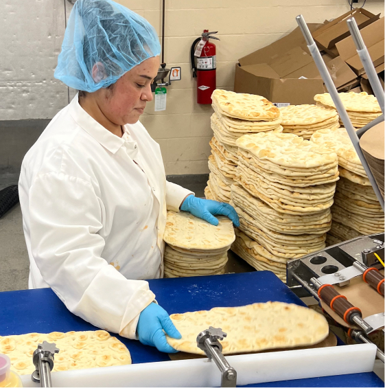 woman taking pizza crusts off conveyor belt